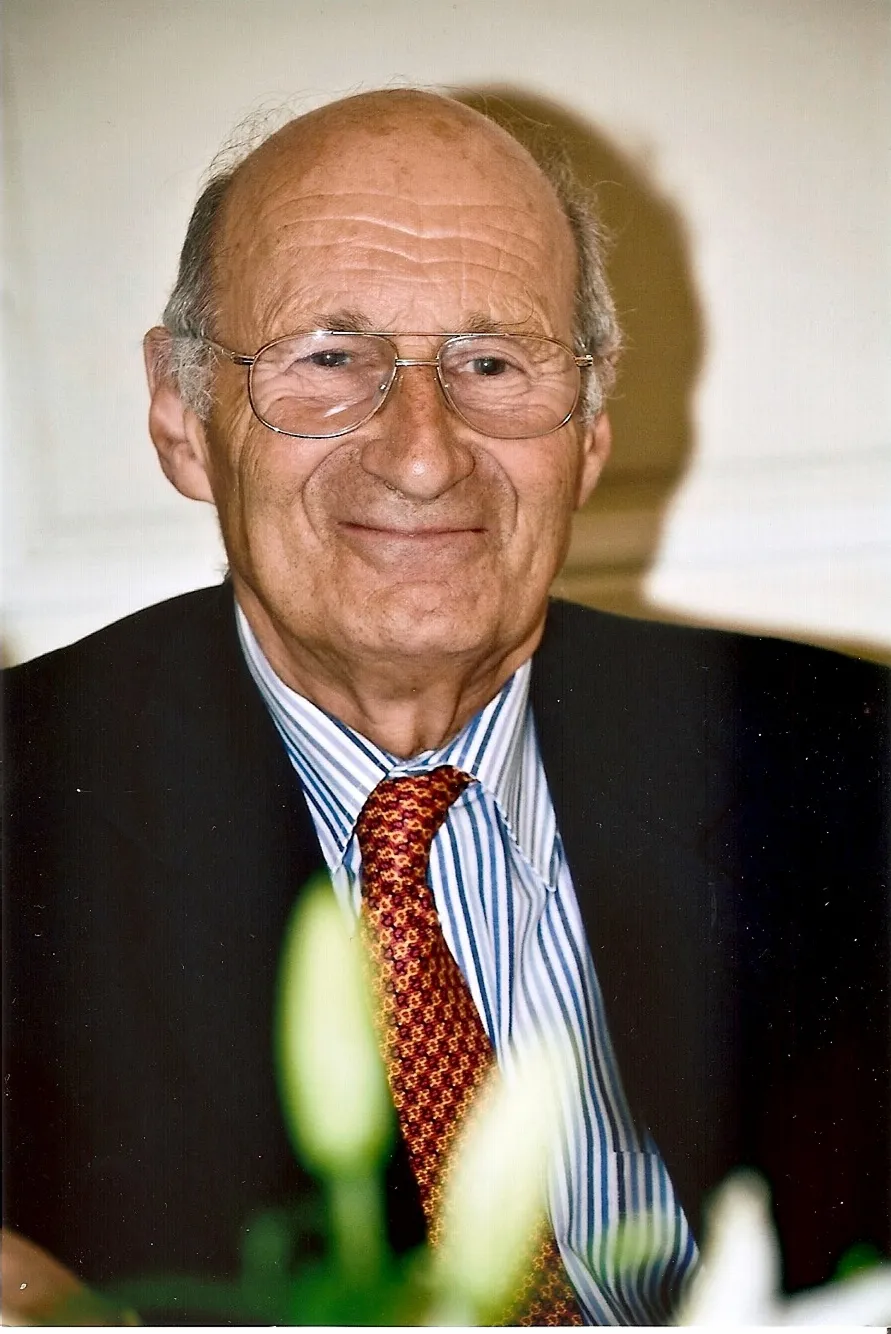 Portrait en couleurs d'Alain Galezowski âgé, souriant, en costume et cravate rouge