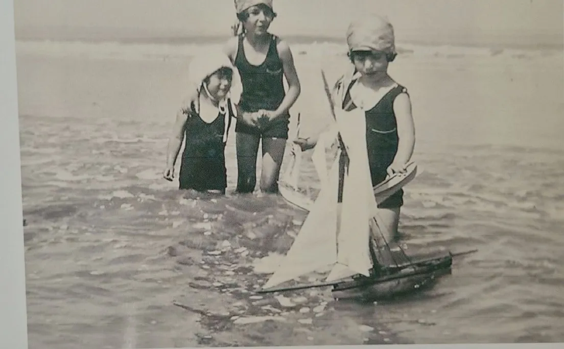 Trois enfants dans la mer avec un voilier miniature