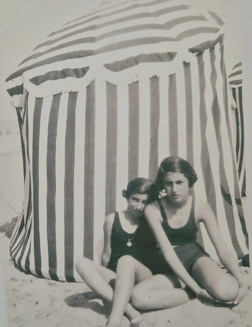 Deux jeunes filles devant une tente rayée sur la plage
